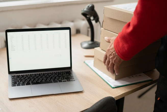 Worker handling packages beside a laptop showing freight forwarder performance metrics